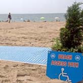 Sign on beach next to beach mat reads Beach Access Path
