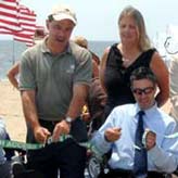 Officials and accessiblity advocates cut ribbon on beach mat
