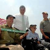 Officials and accessiblity advocates cut ribbon on beach mat