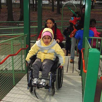 Girl pushing friend in wheelchair in accessible playground