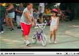 Video still of adult teaching child to ride bike