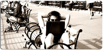Man using laptop on a park bench