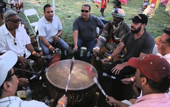 men sit in a circle around a drum