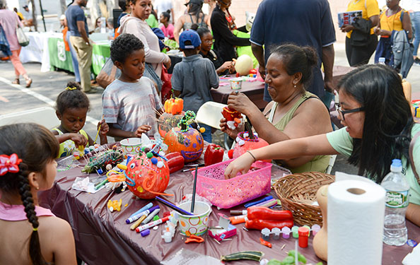 kids and adults participate in an arts and craft activity with pumpkins and stationary